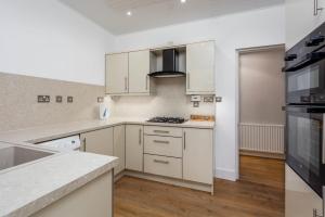 a kitchen with white cabinets and a stove top oven at Seafield House - Donnini Apartments in Ayr