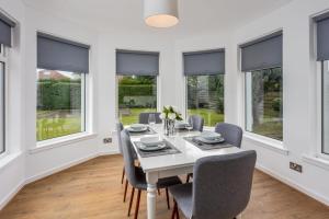 a dining room with a table and chairs and windows at Seafield House - Donnini Apartments in Ayr