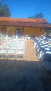 a row of white chairs in front of a building at Chacara desejo do coração dois in Juquitiba