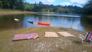 two chairs and umbrellas on the shore of a lake at Chacara desejo do coração dois in Juquitiba +13 photos