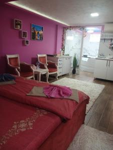 a bedroom with purple walls and a bed and chairs at Stan Na Dan Pancevo in Pančevo