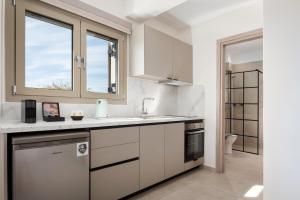a white kitchen with a sink and a window at Fasma Suites in Perdika