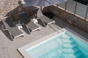 an overhead view of a swimming pool with chairs and an umbrella at Fasma Suites in Perdika