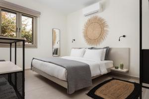 a white bedroom with a bed and a mirror at Fasma Suites in Perdika