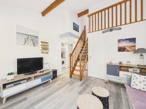 a living room with a tv and a staircase at Maison avec piscine à 200m de la plage in Saint-Michel-Chef-Chef