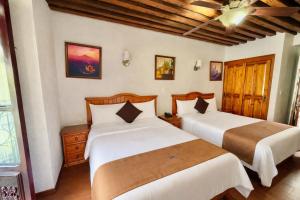 two beds in a room with wooden floors at Hotel Puebla Plaza in Puebla