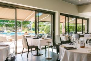 a restaurant with white tables and chairs and a pool at Sous Les Pins in Étoile-sur-Rhône
