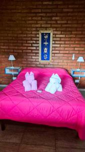 a pink bed with two stuffed animals on it at Caranday in Cortaderas