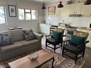 a living room with a couch and chairs and a kitchen at Cedara Way Cottage in Hilton