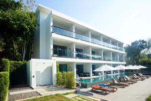 ein Hotel mit einem Pool, Stühlen und Sonnenschirmen in der Unterkunft Moonlight Bed & Brunch - SHA Extra Plus in Ko Lanta