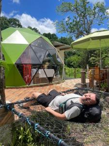 a man laying on the ground next to a tent at The Tortoise Dome Lodge in Bellavista