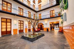 a building with a tree in a courtyard at Hotel Puebla Plaza in Puebla