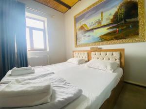 two beds in a bedroom with a painting on the wall at Guest house Afsona old city in Bukhara