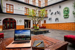 a laptop computer sitting on a wooden table in a courtyard at Hotel Puebla Plaza in Puebla