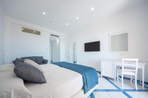 a white bedroom with a bed and a desk at San Francesco Amalfi Coast Hotel in Maiori