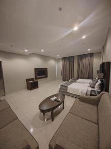 a bedroom with a bed and a couch and a table at فندق تاج النخبة - Taj Nakhba Hotel in Jazan +8 photos