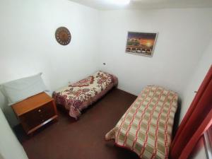 a bedroom with two beds and a table in it at Depto Brochero in Mina Clavero +4 photos