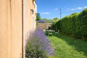 a garden with a purple bush next to a building at Gîte Le Verdon in Quinson