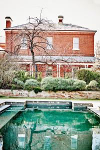 a swimming pool in front of a brick building at Ravenswood Homestead in Ravenswood