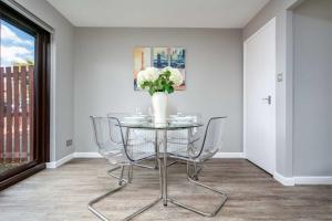 a dining room with a table with chairs and a vase with flowers at The Huntington - Donnini Apartments in Ayr