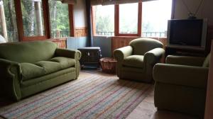 ein Wohnzimmer mit 2 grünen Stühlen und einem TV in der Unterkunft Cabaña Lago Villarrica ideal 2 familias in Villarrica