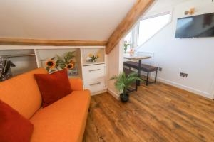 a living room with an orange couch and a table at Seagulls Nest in St Ives
