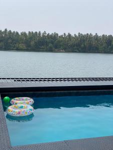 a swimming pool with umbrellas next to a body of water at Riveria By Vstays in Kozhikode