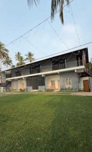 a building with a grass field in front of it at Riveria By Vstays in Kozhikode