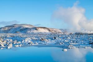 a snow covered mountain in front of a body of water at Northern Light Inn in Grindavík +59 photos