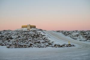 a road with a building on top of a snow covered hill at Northern Light Inn in Grindavík