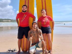 a group of three people standing on the beach with surfboards at Pipa Roots Hostel in Pipa
