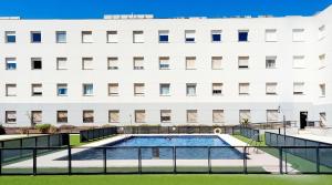 ein Schwimmbad vor einem weißen Gebäude in der Unterkunft Apartamentos Vértice Sevilla Aljarafe in Bormujos