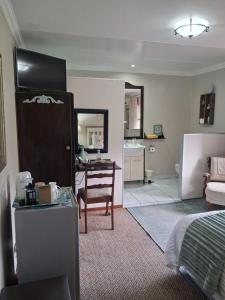 a bedroom with a bed and a table and a chair at Tuscana Villa Guesthouse in Kroonstad