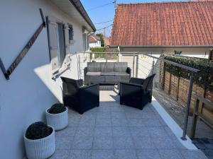 a patio with two chairs and a couch on a balcony at le relais des étangs B in Mareuil-Caubert