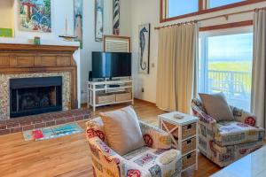 a living room with a fireplace and a tv at 4110 - Coop's Cottage in Duck