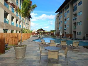 a patio with a table and chairs next to a pool at Flat na Praia dos Carneiros - Resort Max Carneiros Suítes in Tamandaré