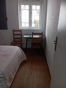 a bedroom with a bed and a table and two chairs at Refúgio da Estrela Covilhã in Covilhã