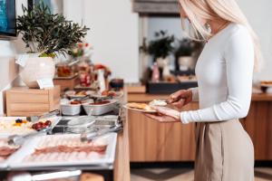 a woman in a kitchen holding a plate of food at Urban Boutique Hotel Center in Ljubljana
