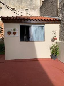 a white building with a window with a blue curtain at Pousada Moradia da Fabi in Bragança Paulista