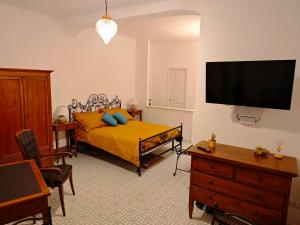 a bedroom with a yellow bed and a flat screen tv at Campagnano Rural Suite & Spa in Ischia Town