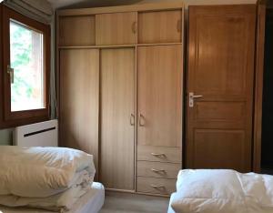 a bedroom with wooden cabinets and a window and two beds at Calm Waters in Doussard
