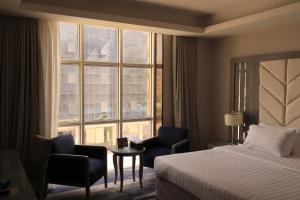 a hotel room with a bed and chairs and a window at Vercure Hotel فندق فيركيور جده الحمراء in Jeddah