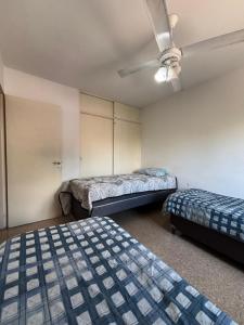 a room with two beds and a ceiling fan at SIERRAS TRAVEL 2f in Villa Carlos Paz +4 photos