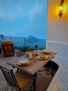 a wooden table with plates and bowls on a balcony at Campagnano Rural Suite & Spa in Ischia Town