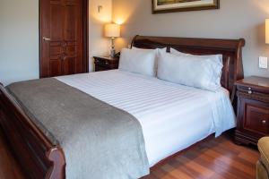 a bedroom with a large white bed with a night stand at Hotel Estelar La Fontana in Bogotá