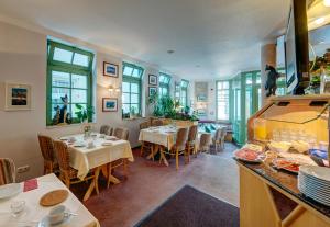 a restaurant with tables and chairs and windows at Hotel zum Kater in Rostock