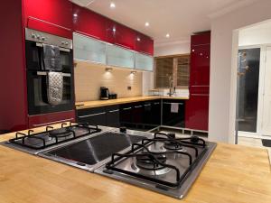a kitchen with red cabinets and a stove top oven at Broadway Pool House with Sauna & Jacuzzi in Herne Bay