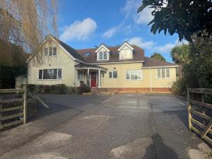 a yellow house with a red door on a driveway at Broadway Pool House with Sauna & Jacuzzi in Herne Bay