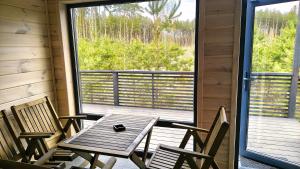 a wooden table and chairs on a porch with a window at Лісове SPA in Vishenki