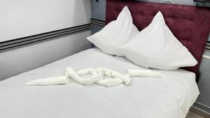 a white bed with white pillows and two bones at "Augustina" apartment in Topliţa